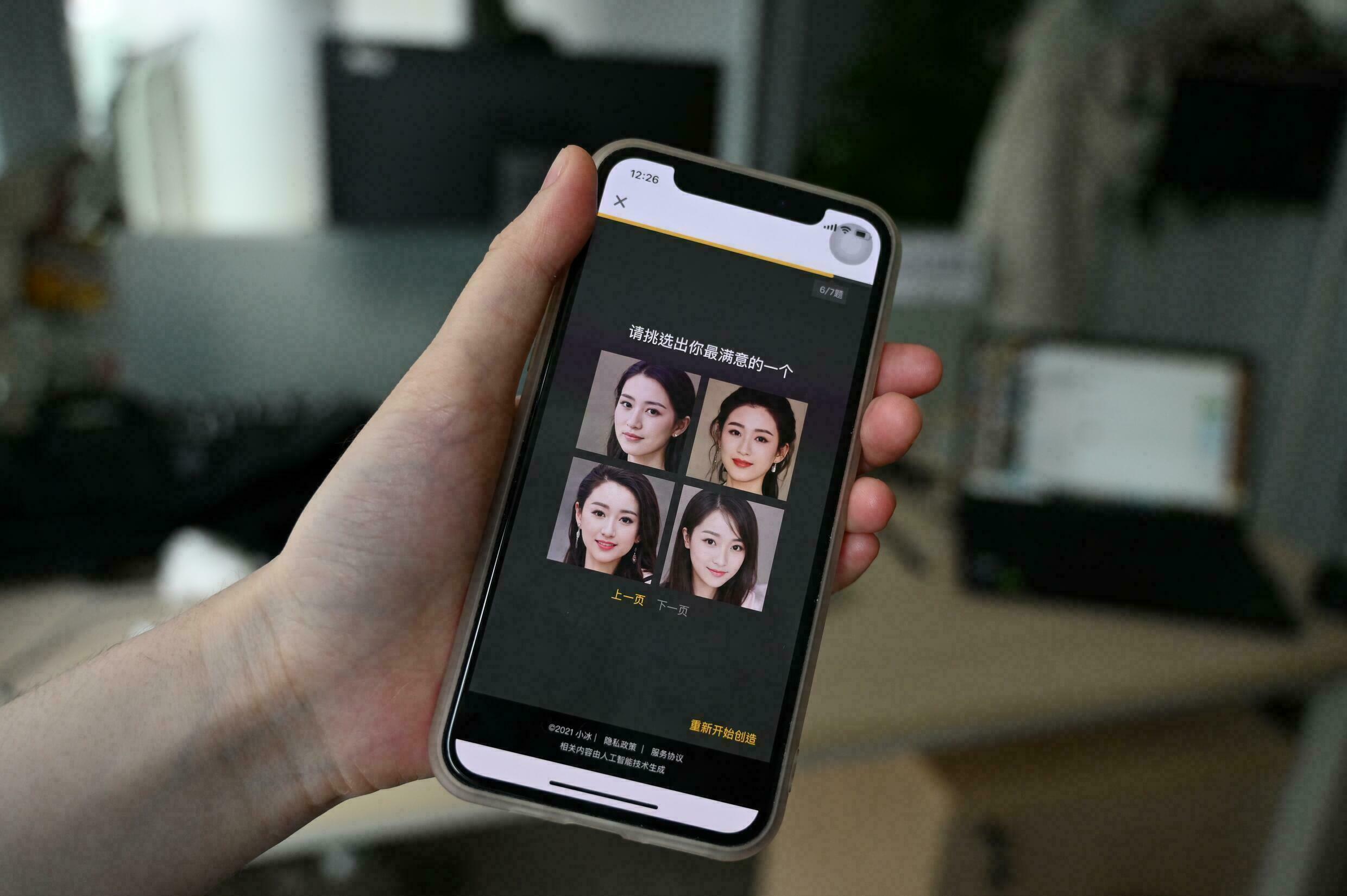 A XiaoIce employee displays photos of virtual women who can be chosen as friends on their smartphones on July 5, 2021 in Beijing