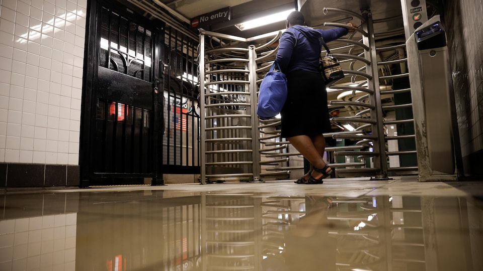 A woman waits at the entrance to the metro station as the floor is almost completely submerged.