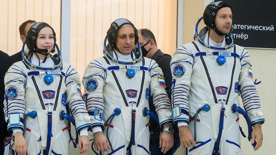 The three wear astronaut suits and stand straight. 