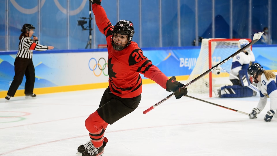 A hockey player raises her arms towards the sky after scoring a goal.