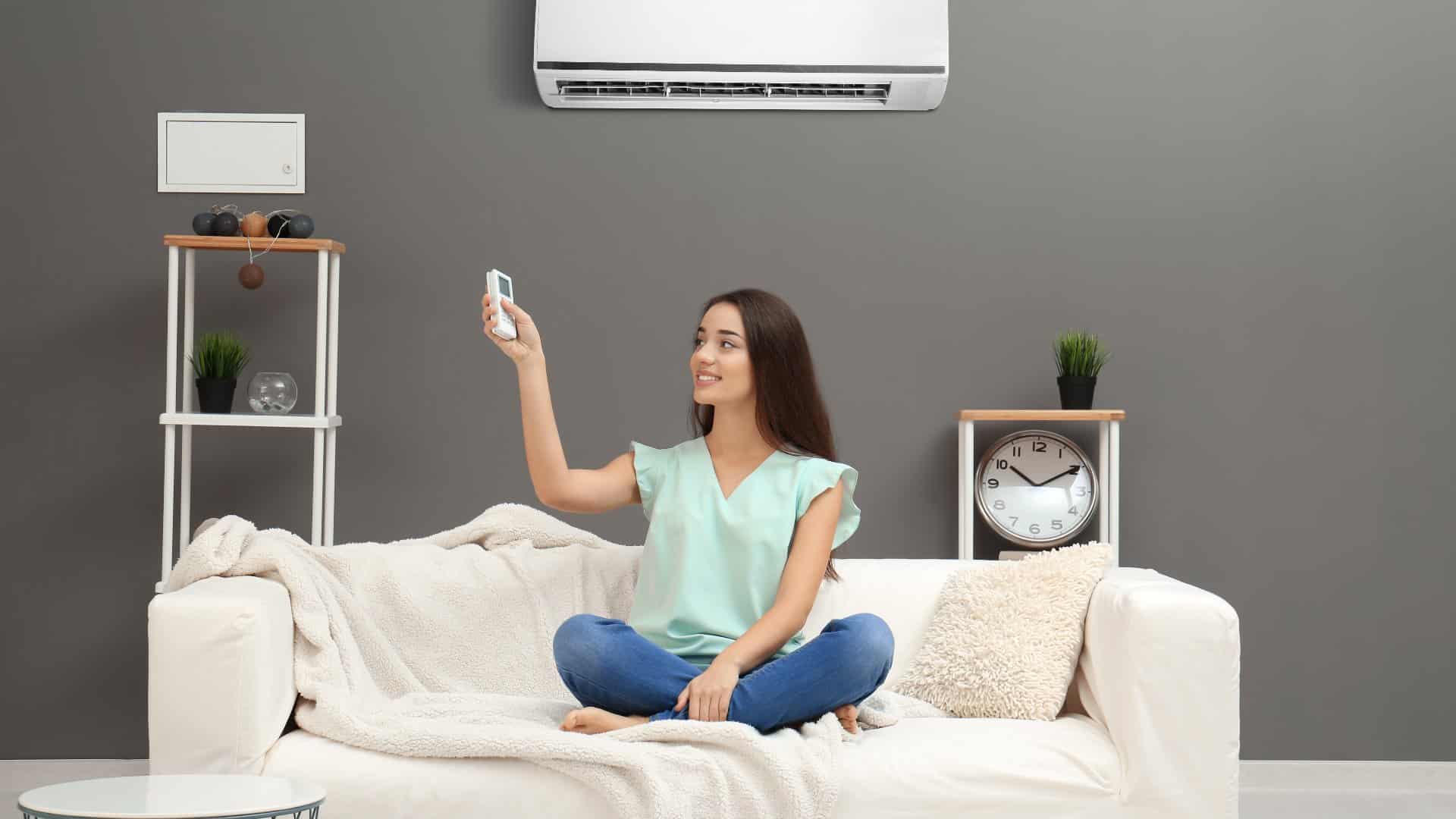 Young woman turning on the air conditioner
